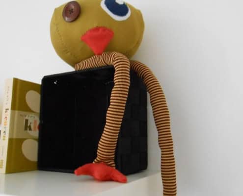 Behang, kinderbehang met een speelse pop met lange armen en een grote oog.