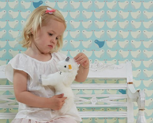 kinderbehang met vogelpatroon in lichtblauw met meisje ervoor