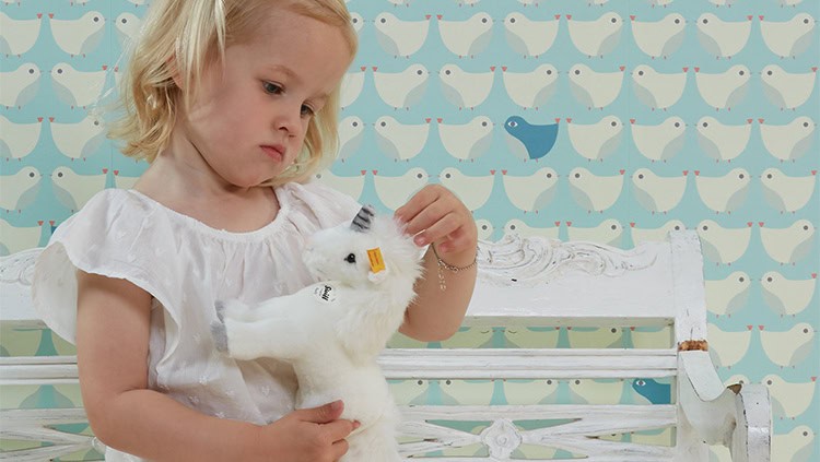 kinderbehang met vogelpatroon in lichtblauw met meisje ervoor