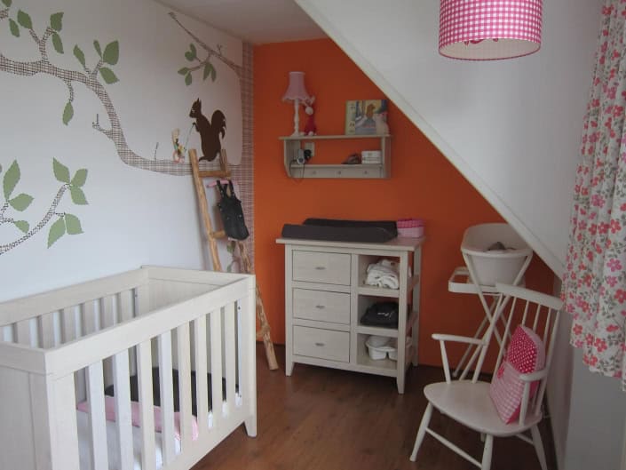 posterbehang-babykamer-oranje-nis Behang en kinderbehang in een kinderkamer onder een schuine muur.